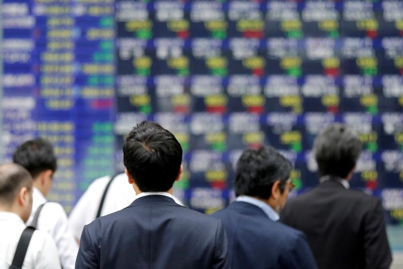People walk past an electronic stock quotation board outside a brokerage in Tokyo, Japan, September 22, 2017. u00e2u20acu201d Reuters picnn