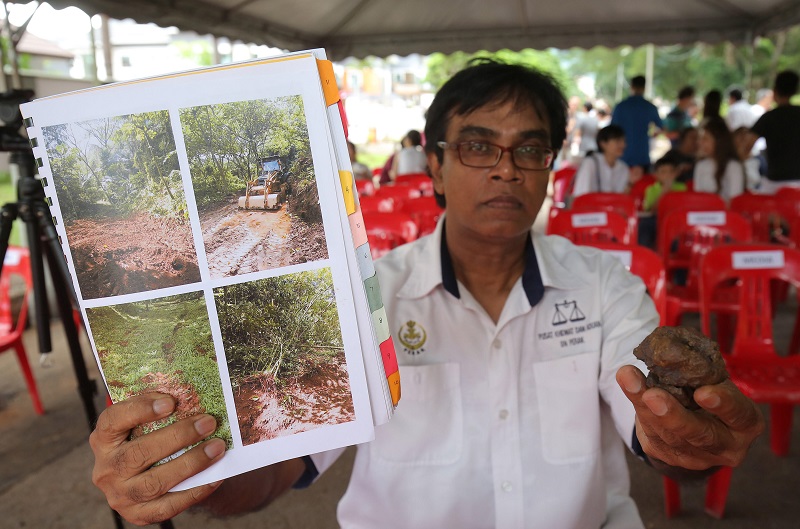 Ipoh Barat Barisan Nasional Public Service and Complaints Centre chief Mohd Rawi Abdullah showing pictures of previous land clearing activity which took place back in 2011. — Picture by Marcus Pheong