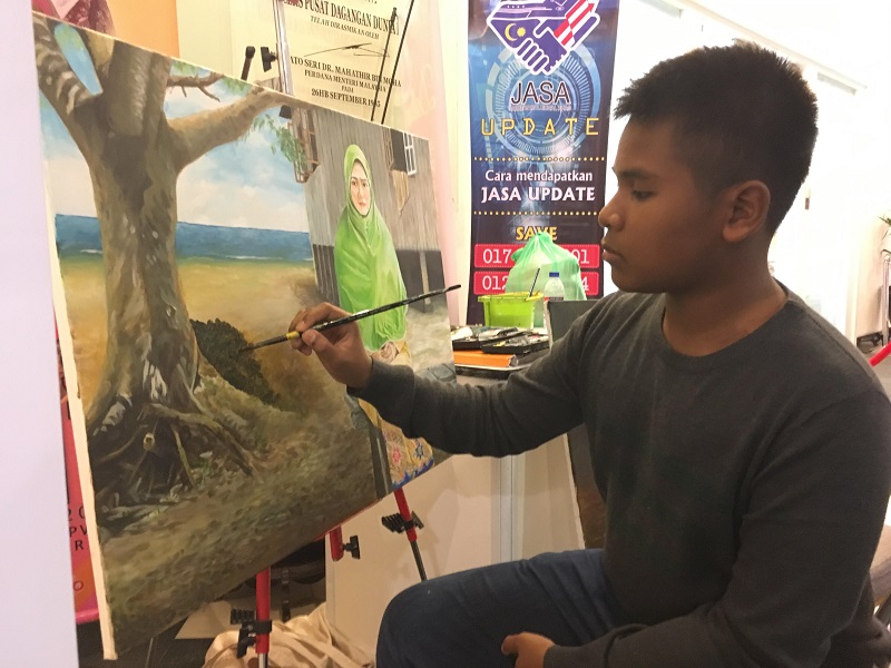 Naim Hamid Hamidi used mostly oil and a bit of acrylic for the lone mangrove painting. His previous work of a woman in a long green headscarf was completed yesterday. u00e2u20acu201d Picture by Jerry Choong