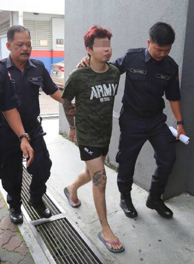 The 22-year-old suspect being escorted out of the Johor Baru courthouse by policemen after his remand was extended today. u00e2u20acu201d Picture by Roslan Khamis