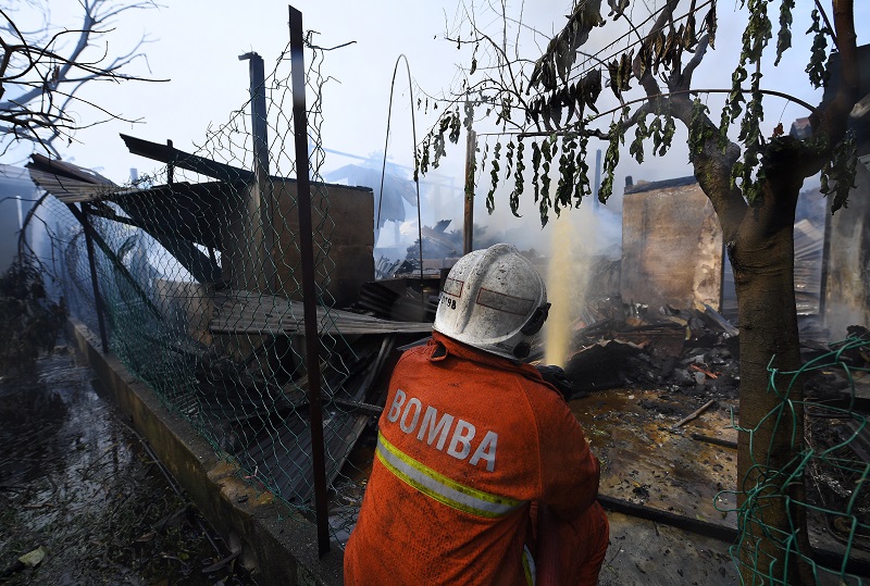 A firefighter tries to extinguish a blaze at Kampung Baru in Kuala Lumpur December 29, 2017. — Bernama pic