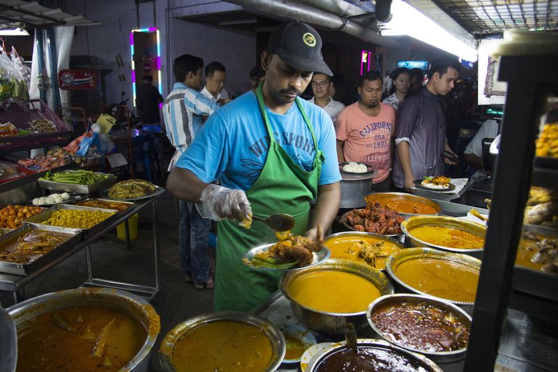 Long queue of customers at the Jamal Mohamed Nasi Kandar stall under a tree, famous for its rich spicy curries and dishes.