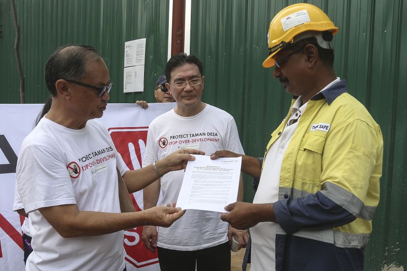 Tiara Faber resident KY Khong hands over a memorandum to contractor Keller (M) Sdn Bhd's site manager M. Chandiran as Protect Taman Desa coalition chairman Frank Yeh looks on. ― Picture by Yusof Mat Isa