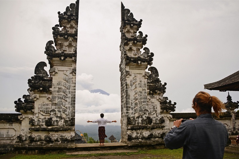 A tourist takes a photo at Lempuyang temple as Mount Agung looms in the background, in Karangasem Regency on Indonesiau00e2u20acu2122s resort island of Bali December 2, 2017. u00e2u20acu201d AFP pic
