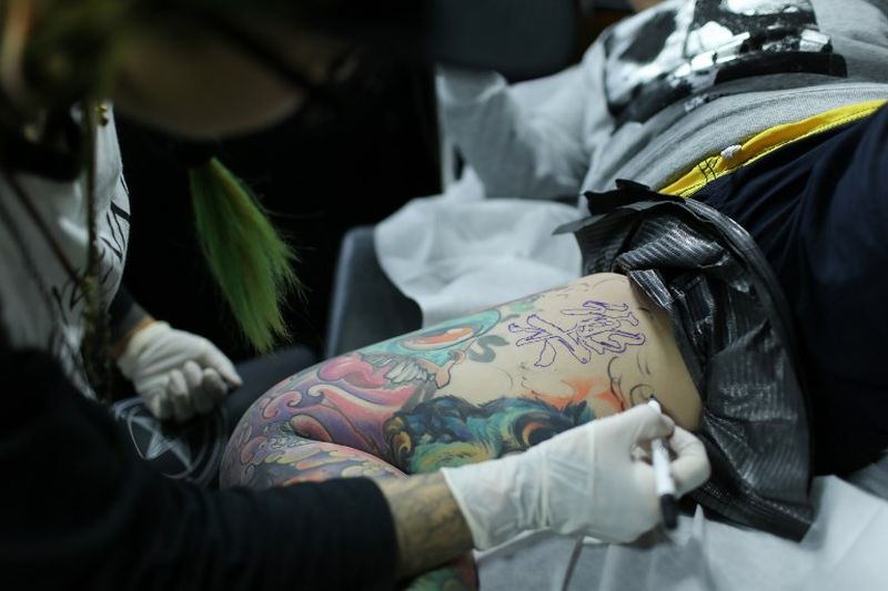 This photo taken on November 29, 2017 shows Wang Qi (right), a web designer and tattoo enthusiast, getting new ink on her right thigh at a studio in Shanghai. u00e2u20acu2022 AFP pic