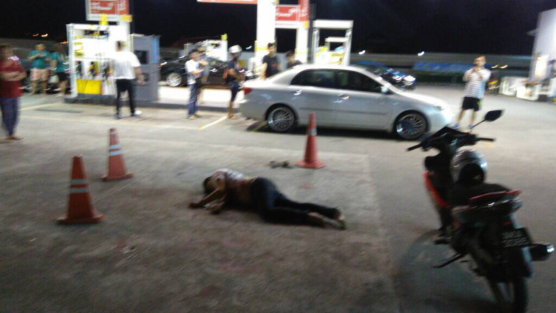 A male motorcyclist lies unconscious at a Shell petrol station along Jalan Sri Pelangi in Taman Pelangi in Johor Baru after he was brutally attacked, stabbed and run over twice by his assailants tonight. u00e2u20acu201d Picture courtesy of the police