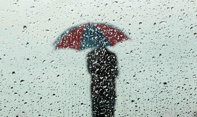 A man carrying an umbrella is seen silhouetted through a window covered with rain drops during a wet day in Colombo December 1, 2017. u00e2u20acu201d Reuters pic
