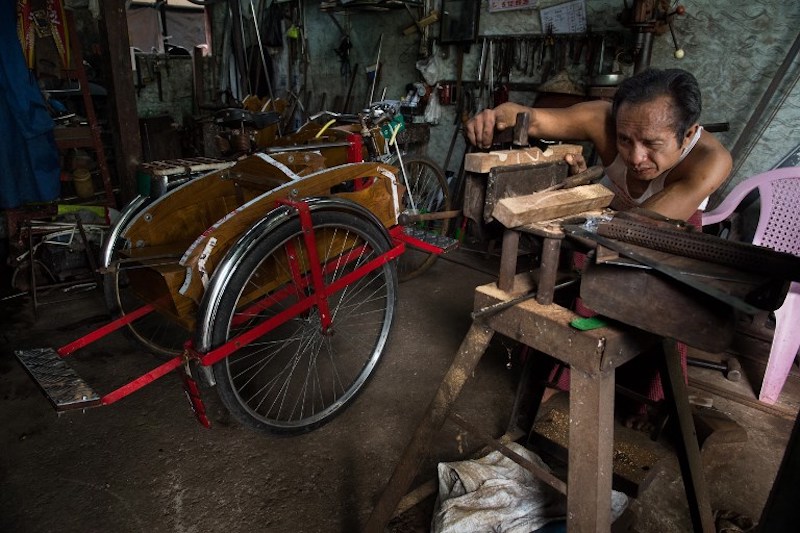 Cycle trishaw maker Aye Zaw carefully lining up a wood support he carved to replace an old one on a used cycle rickshaw in Yangon August 17, 2017. u00e2u20acu201d AFP pic