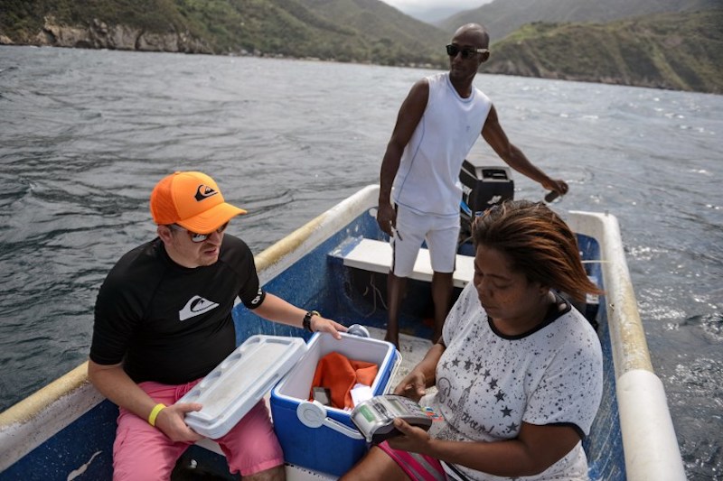 Nancy Rodriguez charges food to a tourist's credit card in a boat, after motoring 2km off the coast of Chichiriviche de la Costa, to find an internet signal, some 70km northwest of Caracas, January 13, 2018. u00e2u20acu201d AFP pic