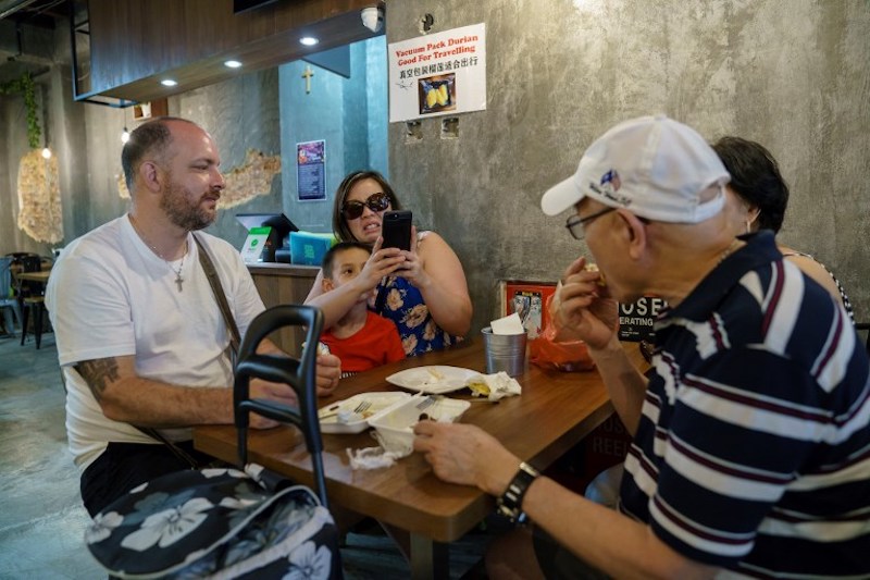 A customer reacts as she watches her family member eat durian at Mao Shan Wang cafe in the Chinatown district of Singapore January 24, 2018. — AFP pic