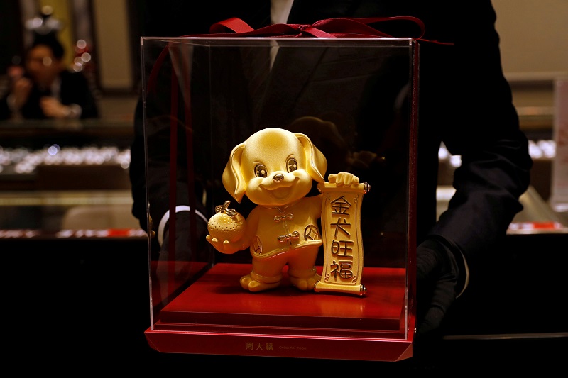 A staff poses with a dog-shaped gold figurine, at Chow Tai Fook Jewellery store ahead of the Lunar Year of the Dog in Hong Kong December 14, 2017. u00e2u20acu201d Reuters pic