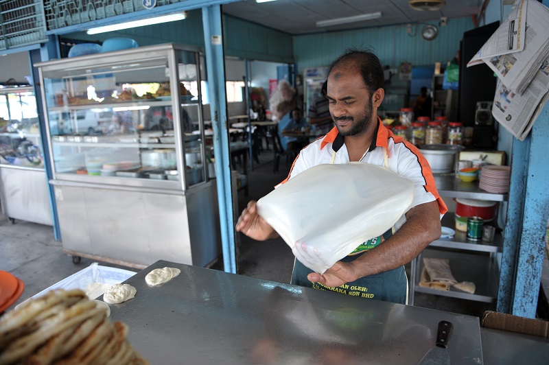 A man prepares roti canai for breakfast at Restoran OMH.
