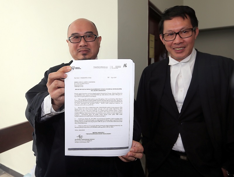 Andrew Soong Tze Toong (left) shows a letter from TNB explaining the remittance of 2.5 per cent rebate into consumers deposit at the Ipoh High Court January 17, 2018. With him is co-counsel YK Cheong (right). u00e2u20acu201d Picture by Farhan Najib