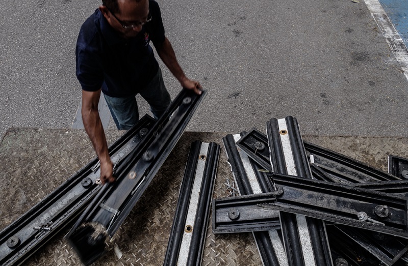 The old separator consists of strips of rubber with metal fasteners to attach it to the divider line on the road.