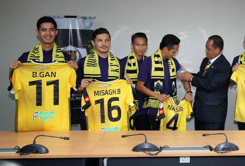 Perak FA president Abdul Puhat Mat (right) places the captainu00e2u20acu2122s armband on Mohd Nasir Basharudin (2nd right), while new signings Brendan Gan (left), Misagh Medina Bahadoran (2nd left) and Nor Hakim Hassan (3rd right) pose with their jerseys. u00e2u20acu201d Picture