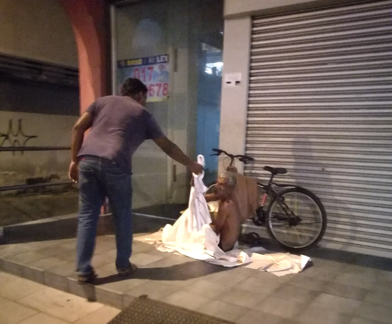 P. Balasundaram handing a blanket to a homeless man on the streets of Ipoh recently.