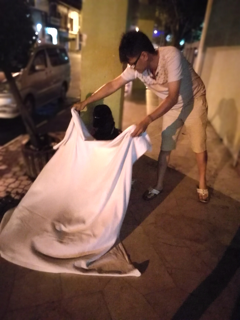 Issac Chin handing a blanket to a homeless man on the streets of Ipoh recently.