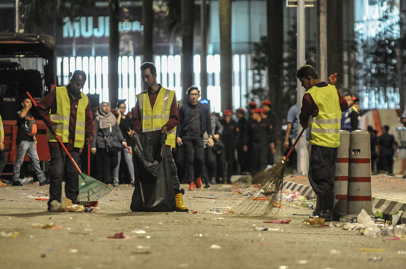 Cleaners are seen sweeping away the rubbish thrown along the road by those celebrating New Year’s Day in KLCC. — Picture by Miera Zulyana 