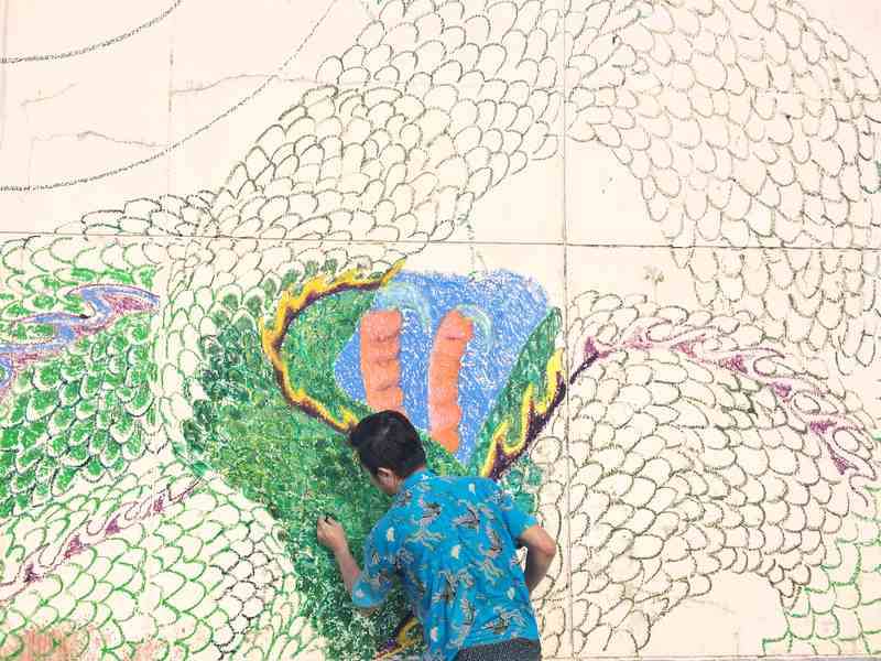 Leong painting a wall mural at Razak Mansion prior to its demolition.