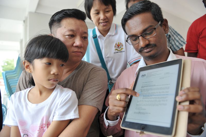 Hng Wei Liang and his daughter, Patcharamai, with Kumaresan showing a 2009 government circular that said any children without Malaysian identification with a Malaysian parent can apply to study in a local school, January 9, 2018. u00e2u20acu201d Picture by KE Ooi