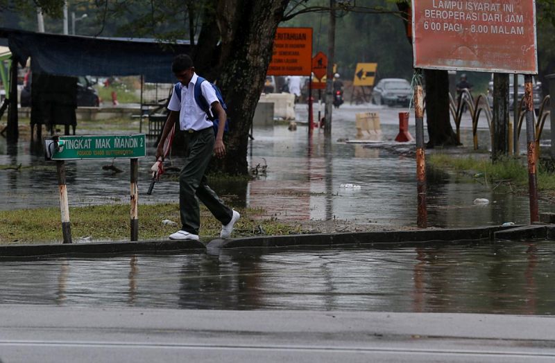 A school boy walks on the high ground as flash flood strikes Mak Mandin area January 5, 2018. u00e2u20acu201d Picture by Sayuti Zainudin 