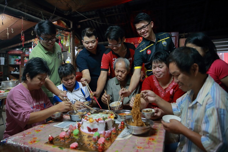 Khaw Hun Leng (centre) and his family members are all smiles as they are joined by volunteers for an early Chinese New Year reunion dinner at their home in Gunung Rapat. u00e2u20acu201d Marcus Pheong
