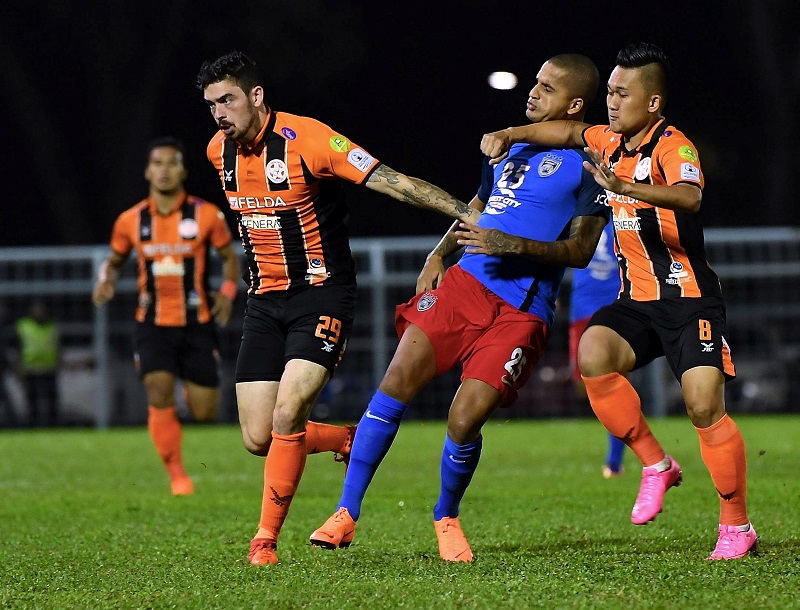 JDT II player Damasceno Neto Murilo (centre) in action against Felda Unitedu00e2u20acu2122s Muhammad Khairul Azrin and Curran Lawrance Sigh Ferns during their match in Johor Baru February 26, 2018. u00e2u20acu201d Bernama pic