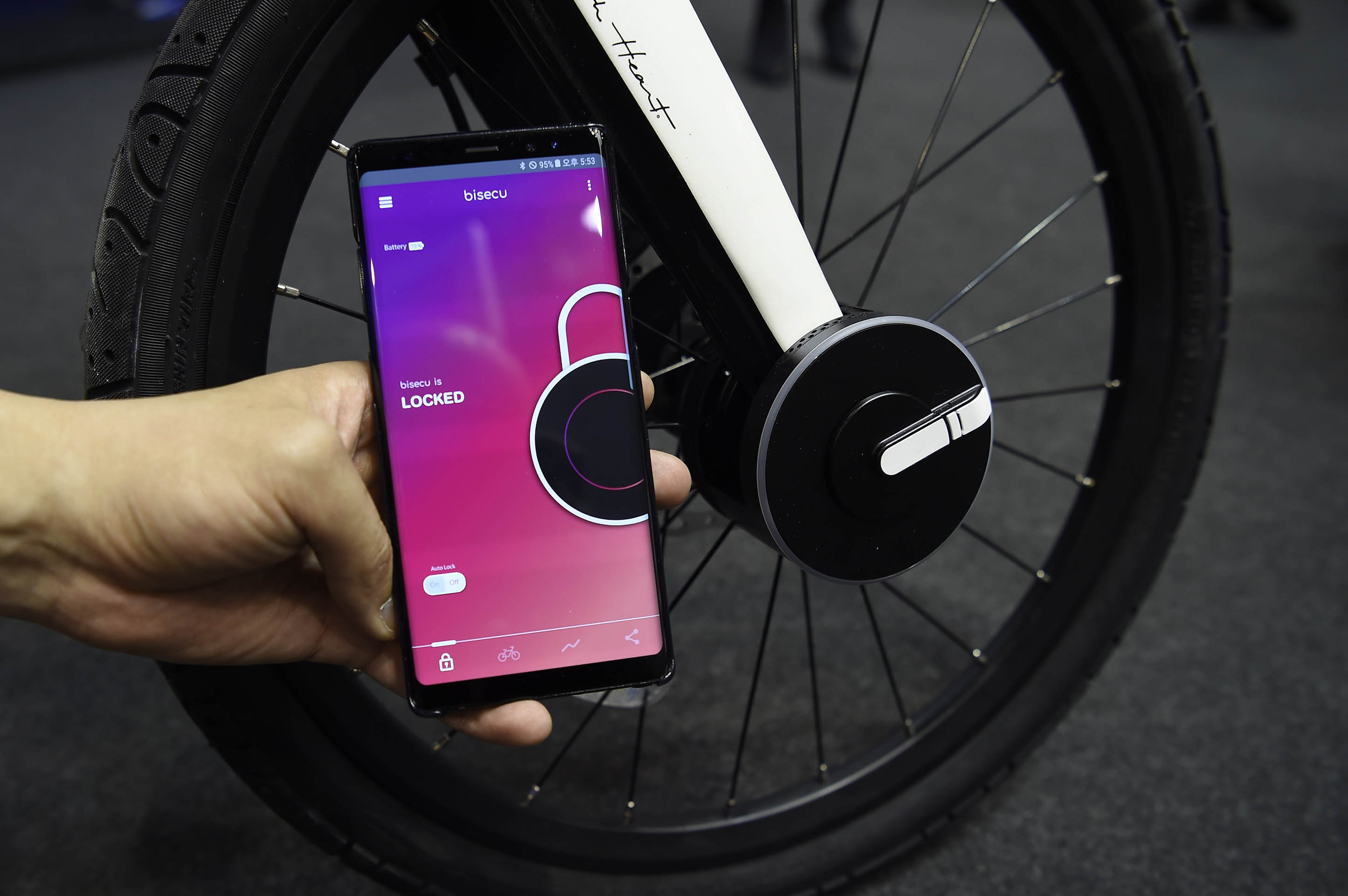A vendor holds a mobile phone used to lock a Bisecu Smart Bike Lock on a bicycle at the Mobile World Congress in Barcelona. u00e2u20acu201d AFP pic