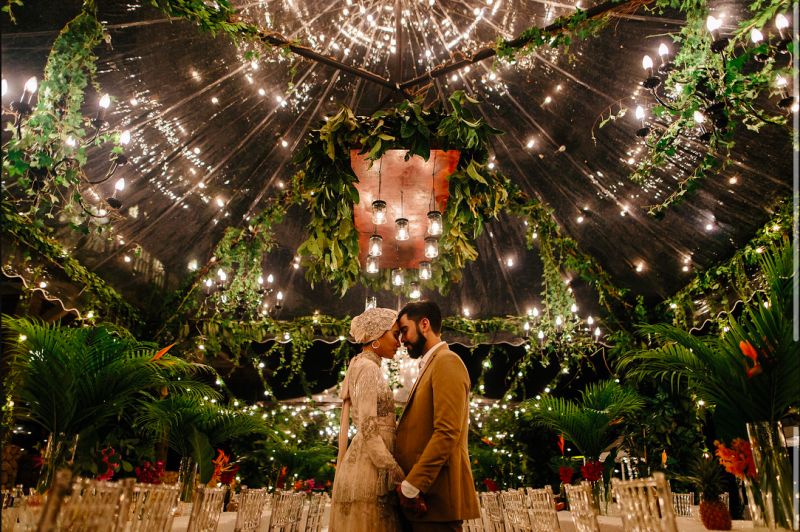 Gorgeous designer canopies adorned with tropical leaves, flowers and lights. u00e2u20acu201d Picture by Weddings by Qay