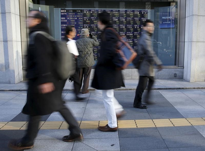 Pedestrians walk past an electronic stock quotation board outside a brokerage in Tokyo, Japan January 20, 2016. u00e2u20acu201d Reuters pic