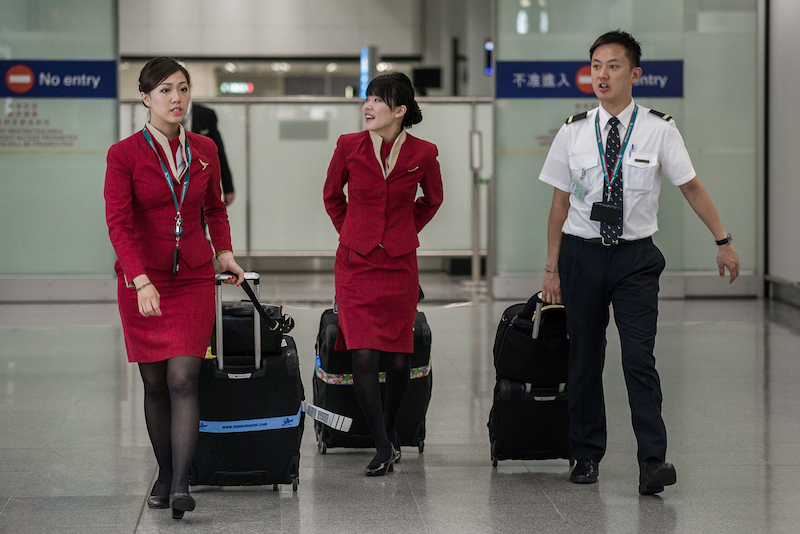 Flight attendants for Cathay Pacific walk with their luggage after arriving at the international airport in Hong Kong. u00e2u20acu201d AFP pic