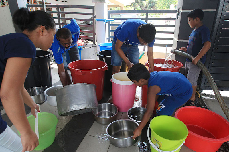 A family from Sanggul Residency 2 Bandar Puteri Klang affected by the water disruption fill up containers with water supplied by an Air Selangor water tanker, March 6, 2018. — Picture by Azinuddiin Ghazali