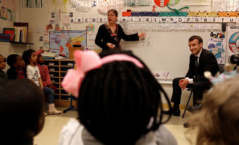 French President Emmanuel Macron (R) listens to teacher Caroline Loret and pre-school children as he visits the Emelie pre-school in Paris, France, March 27, 2018. Christophe Ena/Pool via Reuters