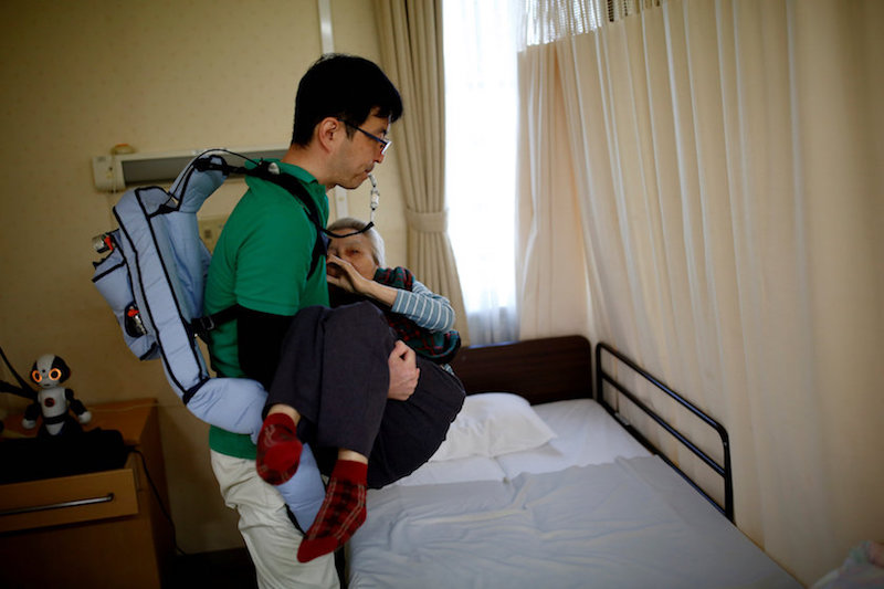 A caretaker wearing a motion assist equipment ‘Muscle Suit’ carries a resident from a bed to a wheelchair at Shin-tomi nursing home in Tokyo February 5, 2018. — Reuters pic