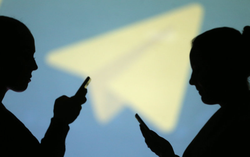 Silhouettes of mobile users are seen next to a screen projection of Telegram logo in this picture illustration taken March 28, 2018. u00e2u20acu201d Reuters pic