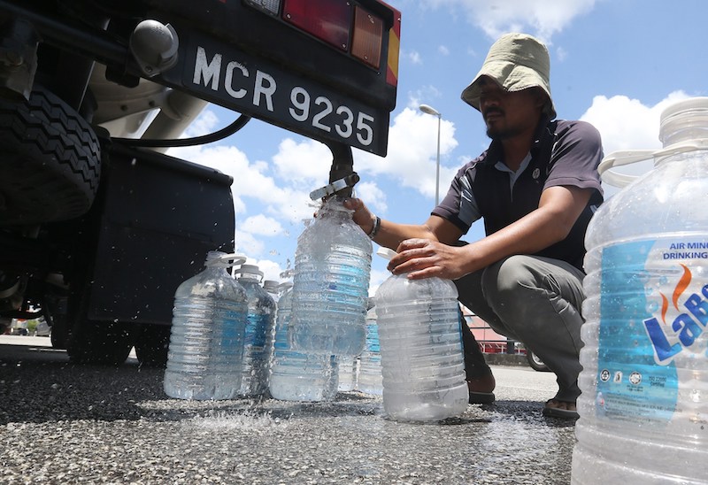 A man fills plastic containers with water from a tanker at a water refilling station near Aeon Big Ampang in Selangor March 8, 2018. u00e2u20acu201d Picture Razak Ghazali