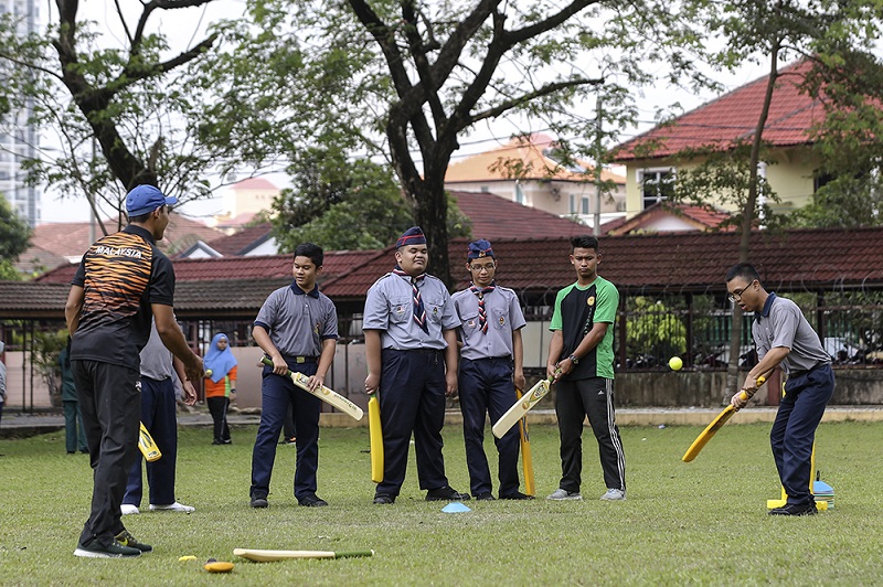 National player Mohd Sukri (left) throws the ball to Syed Aiman Shafie Syed Tarmizi, watched by classmate Nur Iman Izzad (second from right), who plays golf. 