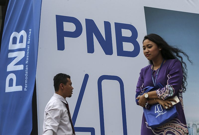 People walk past a Permodalan Nasional Bhd (PNB) logo in Kuala Lumpur March 15, 2018. u00e2u20acu201d Picture by Azneal Ishak