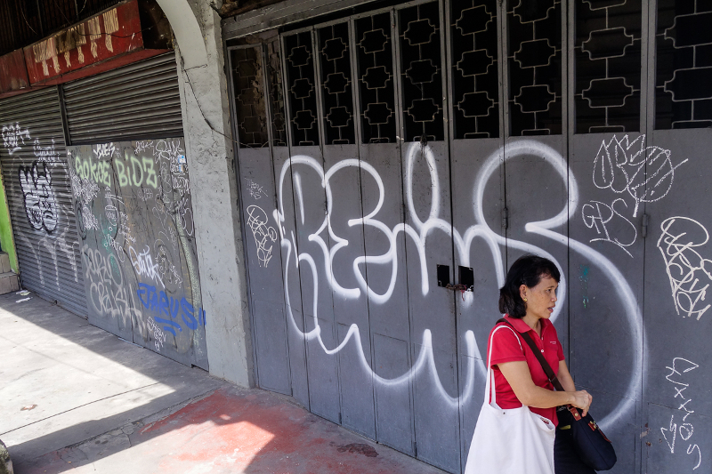 A woman walks past the vandalised entrance of a shop lot at Jalan Tun HS Lee. u00e2u20acu201d Picture by Shafwan Zaidon