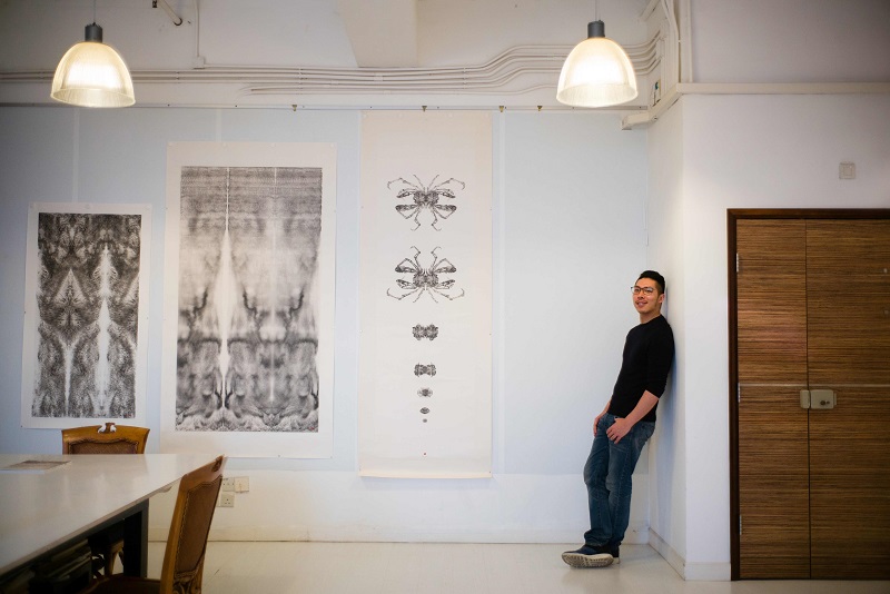 In this picture taken on March 20, 2018, ink artist Hung Fai, 30, who has exhibited at Art Basel four times, poses next to his works (from left) u00e2u20acu02dcSplash XXIIu00e2u20acu2122, u00e2u20acu02dcSplash XIXu00e2u20acu2122 and u00e2u20acu02dcTransformationu00e2u20acu2122 during an interview with AFP at his studio in Hon