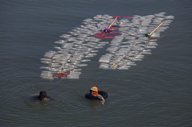 This photo taken on March 21, 2018 shows Indonesian Murni (left) with her fellow villager swimming back to their village with jars of clean water in Tinambung, West Sulawesi. — AFP pic