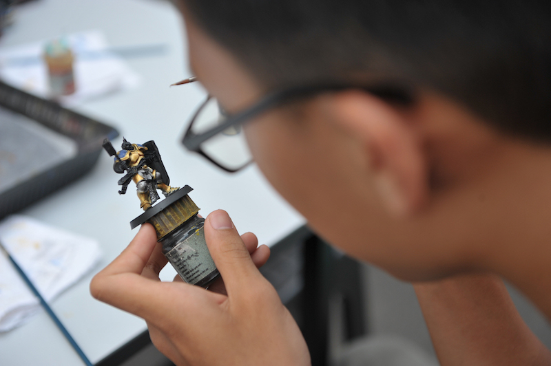 A boy paints a figurine at one of the stalls in Butterworth Art Market. — Picture by KE Ooi