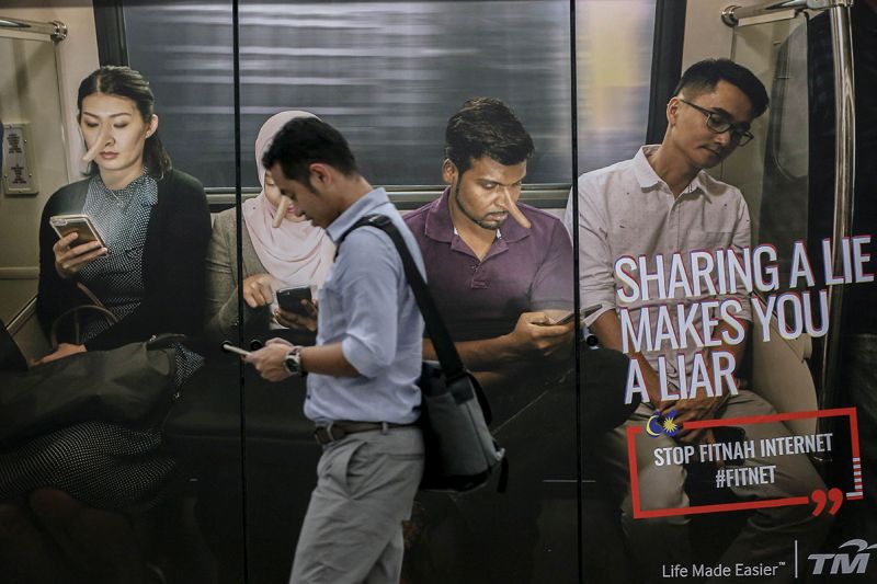 A commuter walks past an advertisement discouraging the dissemination of fake news is pictured at a train station in downtown Kuala Lumpur March 26, 2018. u00e2u20acu201d Picture by Hari Anggara