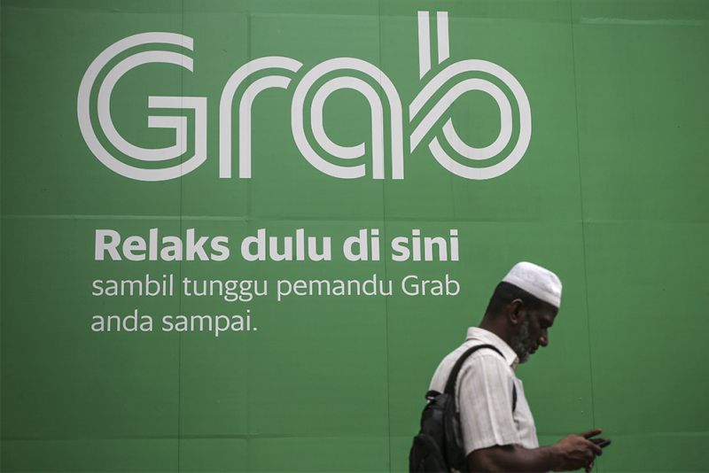 A man walks past a Grab advertisement at Masjid Jamek March 27, 2018. u00e2u20acu2022 Picture by Azneal Ishak