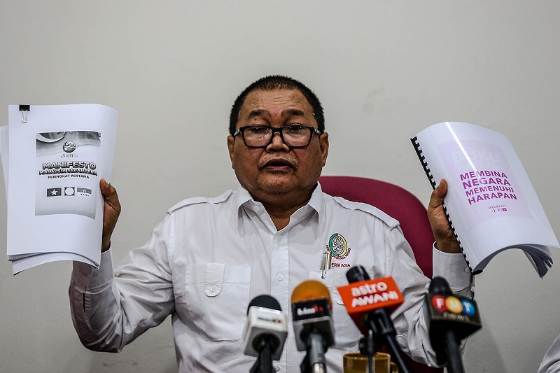Datuk Ibrahim Ali holds copies of Pakatan Harapan and PASu00e2u20acu2122 manifestos during a press conference at Perkasau00e2u20acu2122s headquarters in Kuala Lumpur March 22, 2018. u00e2u20acu2022 Picture by Hari Anggara