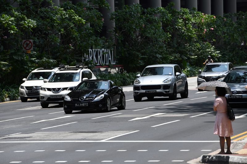 A pedestrian waits at a crossing as cars drive along a street in Singapore, March 15, 2018. The cost of owning a car in space-starved Singapore means it is the worldu00e2u20acu2122s most expensive place to live for the fifth year in a row, a survey said. u00e2u20acu201d AFP pic