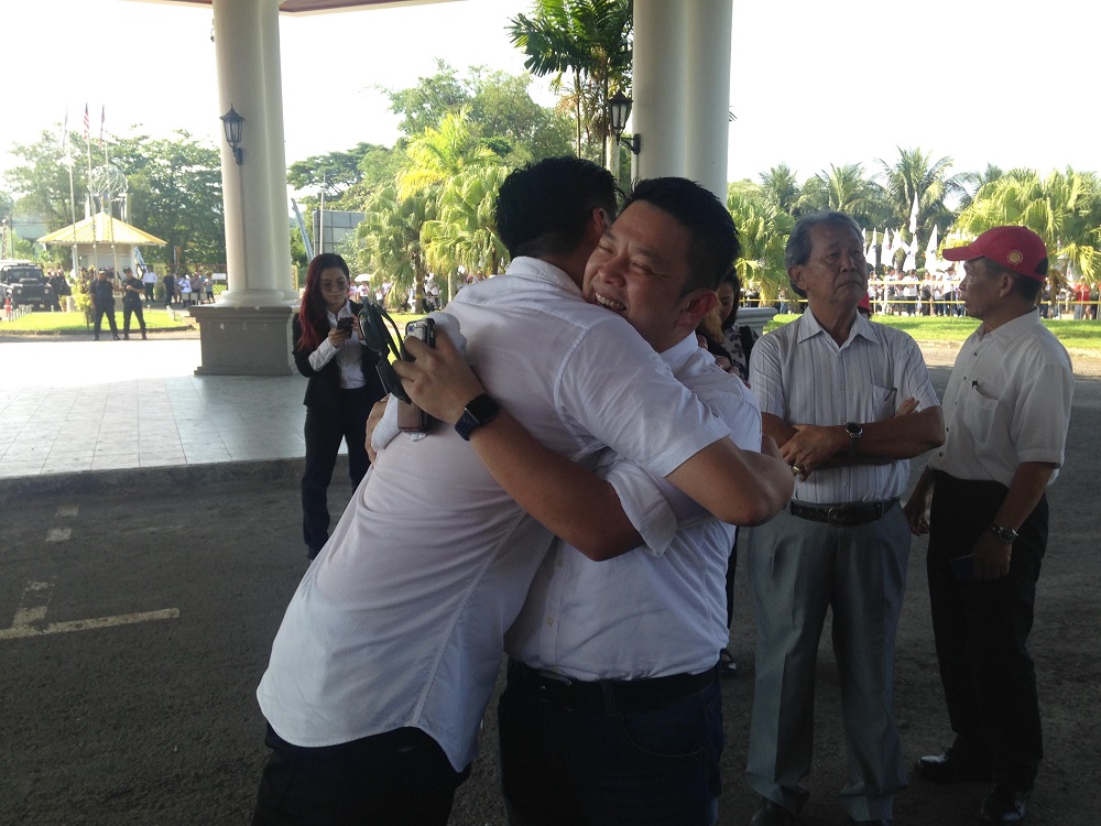 Penampang incumbent Darell Leiking (right) and BN hopeful Ceasar Mandela Malakun wishing each other good luck as they hug outside the Penampang Cultural Centre April 28, 2018. u00e2u20acu201d Picture by Julia Chan
