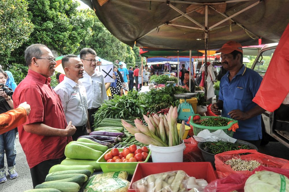 Pakatan Harapan's (from left) Ahmad Ahem, Maszlee Malik and Liew Chin Tong interact with a trader at the Simpang Renggam wet market in Simpang Renggam. — Picture by Shafwan Zaidon