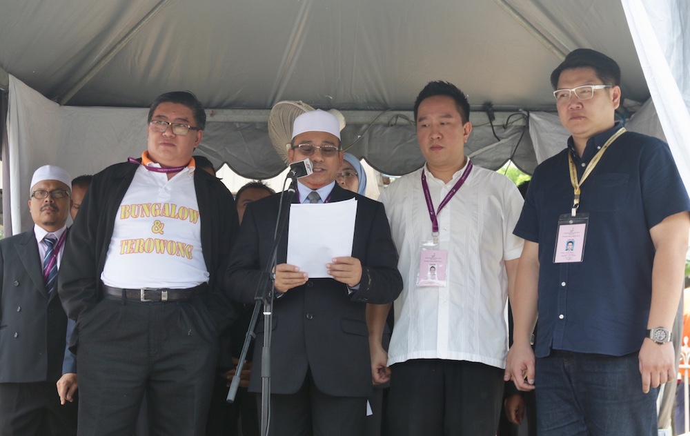 Three of the Bagan candidates PCM Datuk Huan Cheng Guan (left), BNu00e2u20acu2122s Datuk Lee Beng Seng and MUPu00e2u20acu2122s Koay Xing Boon (right) stand alongside returning officer Datuk Rozali Mohamud on Nomination Day April 28, 2018. u00e2u20acu201d Picture by KE Ooi