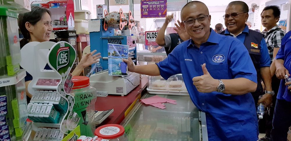 Barisan Nasional candidate Datuk Rozman Isli distributes the Labuan BN manifesto to hawkers at Pasar Sentral, Labuan April 30, 2018. u00e2u20acu201d Bernama pic